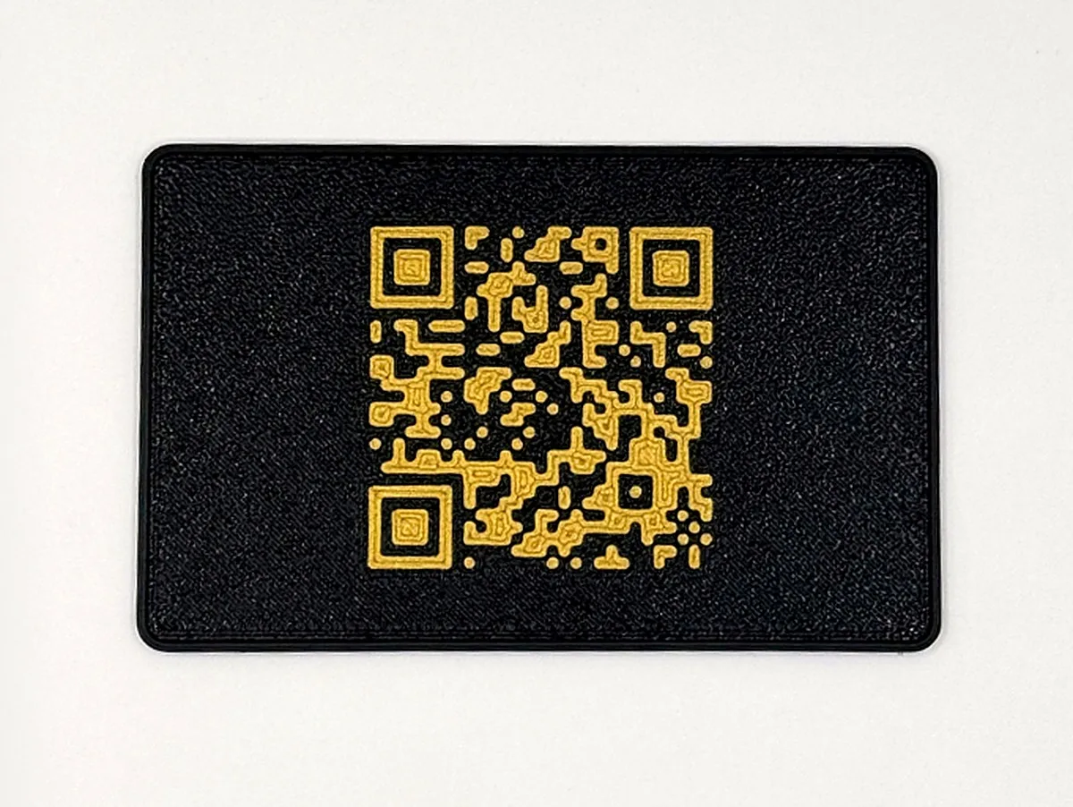 Carte noire imprimée en 3D portant un grand QR code doré en relief
